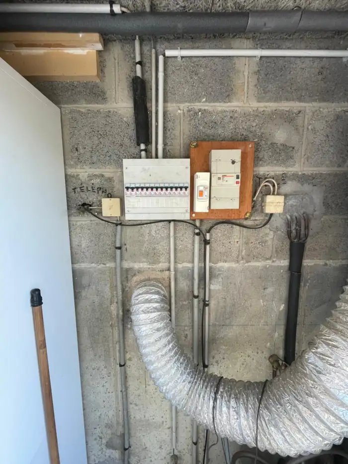Avant : ancien tableau électrique vétuste sur mur en parpaing