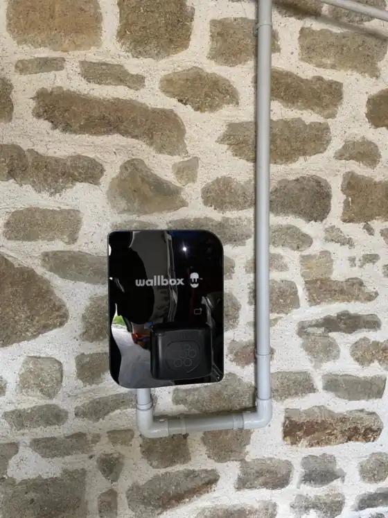 Borne de recharge Wallbox posée sur un mur en pierre